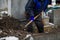 Details of a gravedigger covering a tomb with dirt with a shovel during a burial ceremony on a cold and snowy winter day