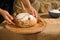 Details: hands on a loaf of warm traditional homemade whole grain sourdough wheat bread on a wooden board