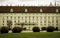 Details of Hofburg Imperial Palace building architecture with lots of windows and doors facade in pastel color and grass field