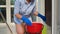 Details: housewife's hands pouring cleaner detergent into a red bucket, for mopping the floor while cleaning the