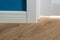Details in the interior. Laminated parquet floors immitating oak texture, white baseboard, white door.