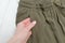 Details of khaki pants in a female hand. Fashionable concept