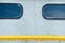 Details of an old electrical locomotive body. Windows, and yellow line on the gray colored hull. Minimalistic photography