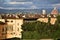 Details of Palazzo Pitti illuminated by the sun, beyond the center of Florence silhouetted in the cloudy sky.