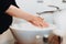 Details of pregnant woman with baby bump washing hands with soap and tap water