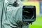 Details of a professional television camera, with rain cover, live broadcasting a soccer game