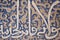 Details of stucco decoration with an Arabic writings painted in blue on the Palaces walls in Alhambra complex, Granada, Andalusia