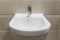 Details of white ceramic bidet with a running water in modern bathroom.