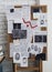 Detective board with fingerprints, crime scene photos and map near white brick wall indoors