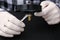 Detective exploring bullet shell with magnifying glass on black background, closeup