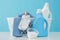 Detergents and children`s clothes on white table near light wall