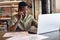 Determined african american businessman with disability talking on phone and using laptop