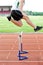 Determined male athlete jumping above hedge