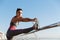 Determined sportswoman stretching leg on a pier and looking along the seaside promenade, warming-up before jogging