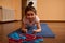 Determined sporty little girl doing plank exercise on a blue fitness mat while working out and stretching body indoors