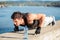 Determined young man doing push-ups on a riverbank