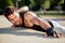 Determined young man doing push-ups on a riverbank