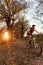 Determined young man riding mountain bike through the forest during sunset