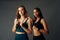 Determined young woman with friend in sports clothing looking at camera while holding jump rope