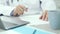 Determining treatment. Close up of hands of middle aged doctor sitting at the desk of his office with laptop, making