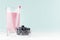 Detox milk violet drink with striped straw, ripe blueberry in bowl on soft pastel blue background and white wood table, copy space