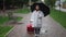 Devastated depressed little woman crying standing on city street with umbrella and travel bag. Wide shot portrait of