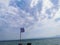 The developing flag of Greece on the background of the Mediterranean Sea. View from the pier to the water