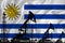 Developing Flag of Uruguay. Silhouette of drilling rigs and oil rigs on a flag background. Oil and gas industry. The concept of