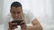 Device addicted young African American man gaming online on smartphone lying in bed in the morning. Portrait of absorbed