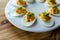 Deviled eggs with paprika and green onions on a white egg platter and wood background. Copy space.
