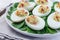 Deviled eggs stuffed with avocado, egg yolk and mayonnaise filling, garnished with bacon on spinach leaves horizontal