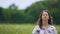 Devoted young woman sits with eyes closed and meditates outdoors, feeling wind