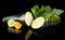 Dewed zucchini cut into slices with flower and leaf on black