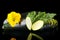 Dewed zucchini cut into slices with flower and leaf on black