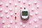 Diabetes concept. Digital glucometer, lancet pen and sugar cubes on a pink background, flat lay. Close-up