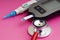 Diabetes concept. Syringe, Glucometer or Glucose meter and stethoscope on pink background