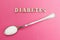 Diabetes inscription, spoon with sugar on a pink background, concept
