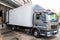 Diagonak view of gray truck delivering food products into shop