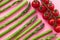 Diagonal composition of asparagus stems and branch of cherry tomatoes on pink paper background.