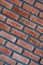 Diagonal front angle of a red brick wall. Close up view of cracked weathered brickwork material. Modern interior design, unique