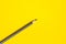 Diagonal gray sharp wooden pencil on a bright yellow background, isolated, copy space, mock up