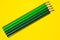 Diagonal green sharp wooden pencils on a bright yellow background, isolated, copy space, mock up