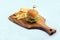 Diagonal Hero Shot of a grilled chicken slider burger, fries on a wooden platter board, on a minimal white background with a