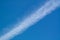 Diagonal line clouds trace of flied jet on a blue sky background