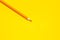 Diagonal orange sharp wooden pencil on a bright yellow background, isolated, copy space, mock up