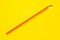 Diagonal orange sharp wooden pencil on a bright yellow background, isolated, copy space, mock up