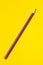 Diagonal purple sharp wooden pencil on a bright yellow background, isolated, copy space, mock up