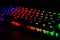 Diagonal RGB gaming keyboard bokeh background. Colorful mechanical keyboard in dark room. Gaming and technology concept
