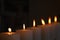 a diagonal row of 6 flickering solemn candles with yellow flames