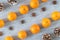 Diagonal rows of oranges, star anise, and pinecones on grey background